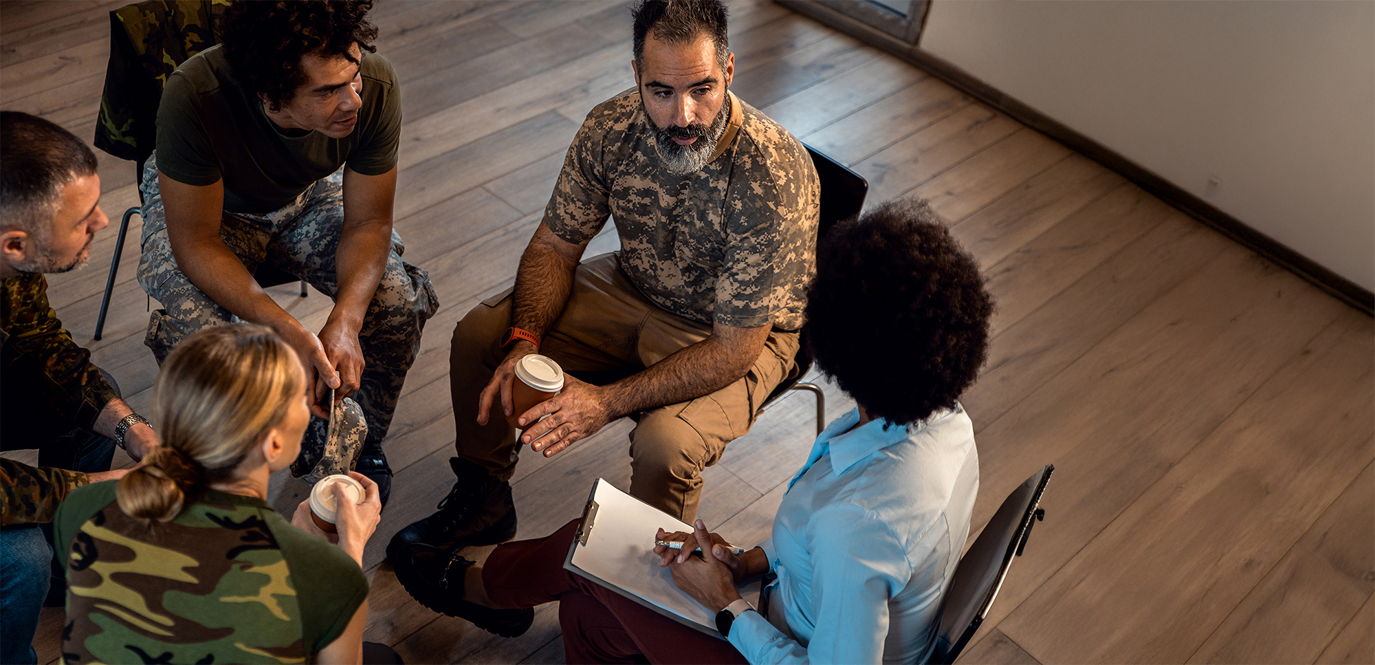Group of diverse veterans talking during PTSD support group.